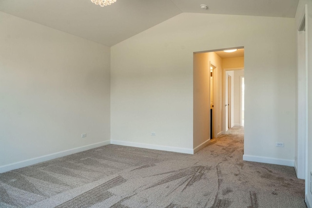 carpeted spare room featuring vaulted ceiling