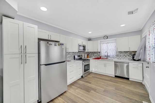 kitchen featuring white cabinets, sink, decorative backsplash, light wood-type flooring, and stainless steel appliances