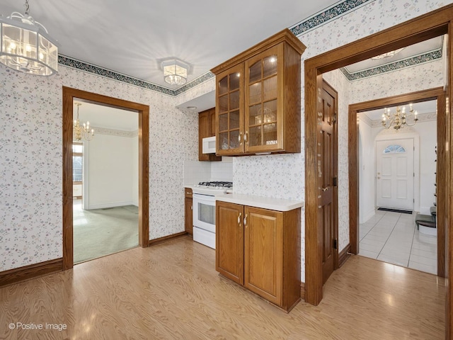 kitchen with light wood-type flooring, white appliances, decorative light fixtures, and a chandelier