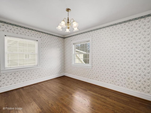 empty room with crown molding, hardwood / wood-style floors, and an inviting chandelier