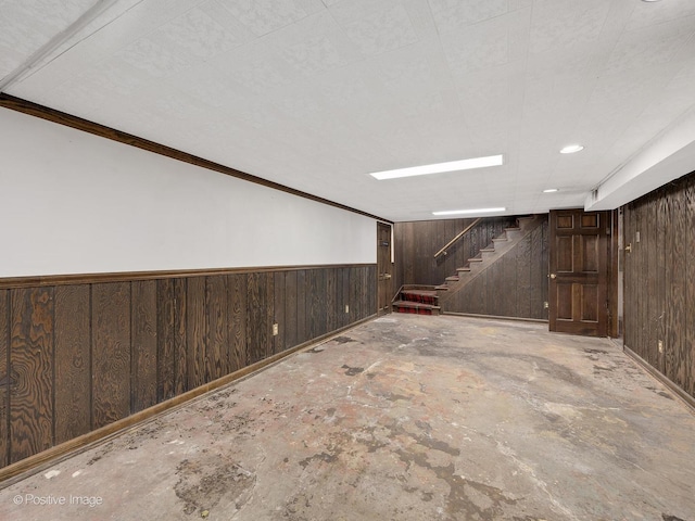 basement with wood walls and crown molding