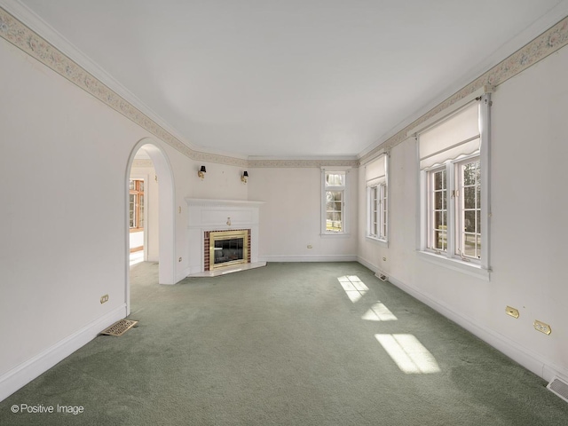 unfurnished living room featuring carpet flooring, a brick fireplace, and crown molding