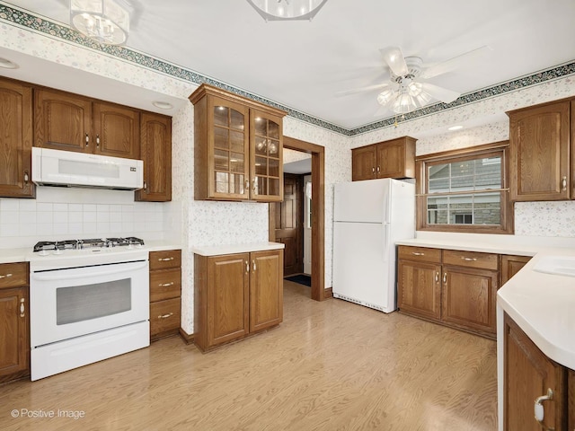 kitchen featuring white appliances, sink, light hardwood / wood-style flooring, ceiling fan, and decorative backsplash