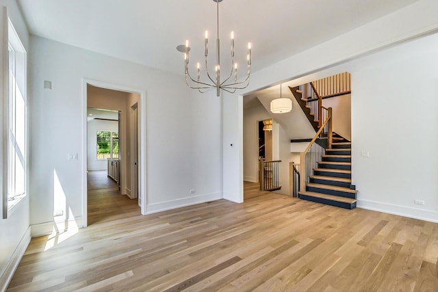 empty room featuring a chandelier and light hardwood / wood-style flooring