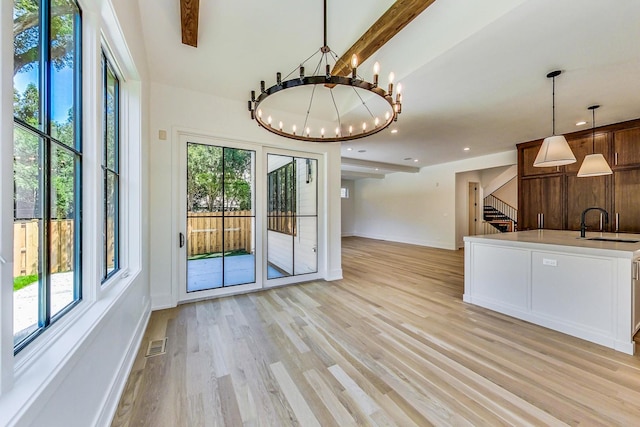 unfurnished dining area with beam ceiling, light hardwood / wood-style floors, plenty of natural light, and a notable chandelier