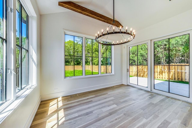 unfurnished sunroom featuring a healthy amount of sunlight, lofted ceiling with beams, and an inviting chandelier