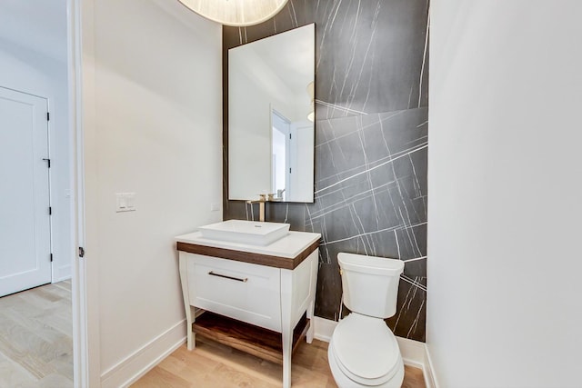 bathroom featuring vanity, toilet, wood-type flooring, and tile walls