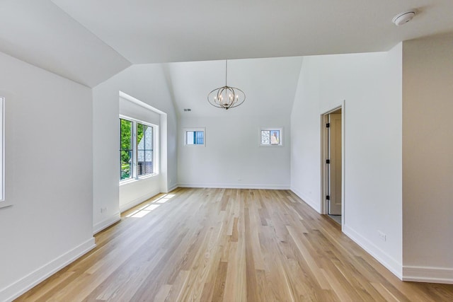 interior space with light hardwood / wood-style floors, vaulted ceiling, and a notable chandelier