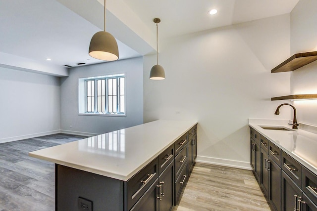 kitchen with kitchen peninsula, decorative light fixtures, light hardwood / wood-style floors, and sink