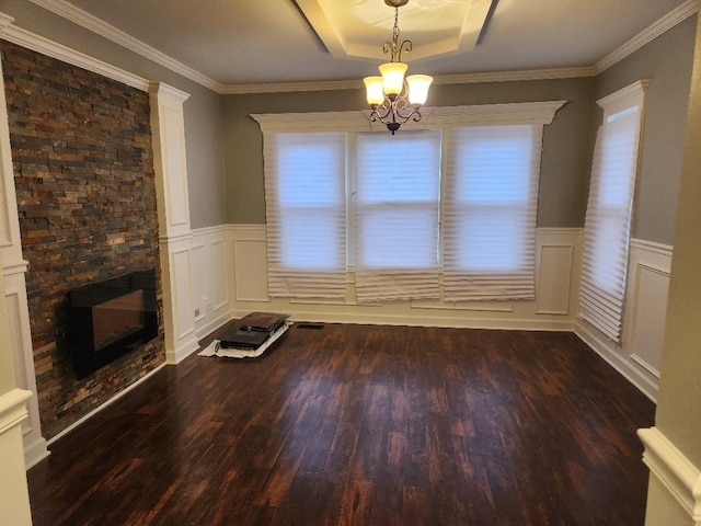 unfurnished dining area featuring a raised ceiling, a stone fireplace, a wealth of natural light, and a notable chandelier