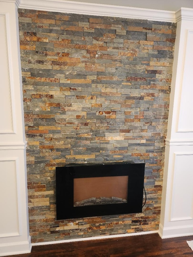 interior details featuring a fireplace, wood-type flooring, and crown molding