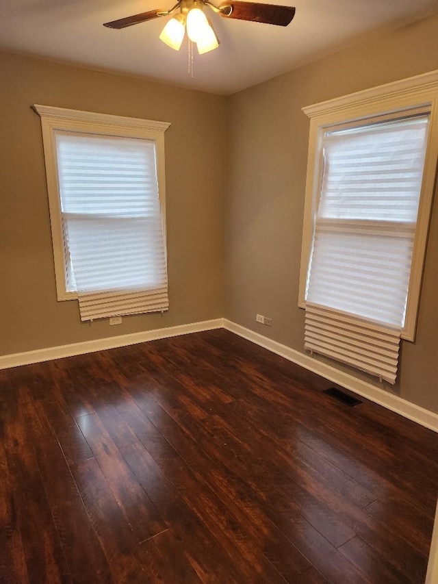 spare room with ceiling fan, a healthy amount of sunlight, and dark hardwood / wood-style floors