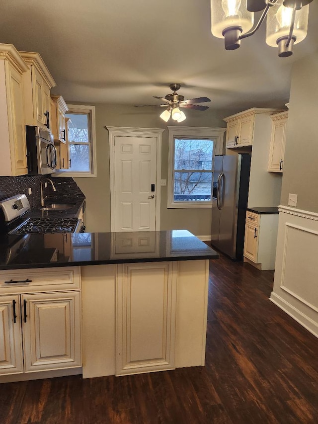 kitchen with ceiling fan with notable chandelier, sink, dark hardwood / wood-style floors, appliances with stainless steel finishes, and kitchen peninsula