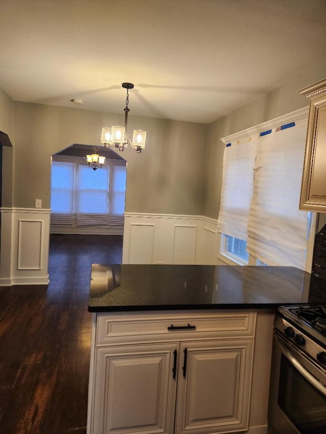 kitchen featuring gas stove, dark wood-type flooring, pendant lighting, and a notable chandelier