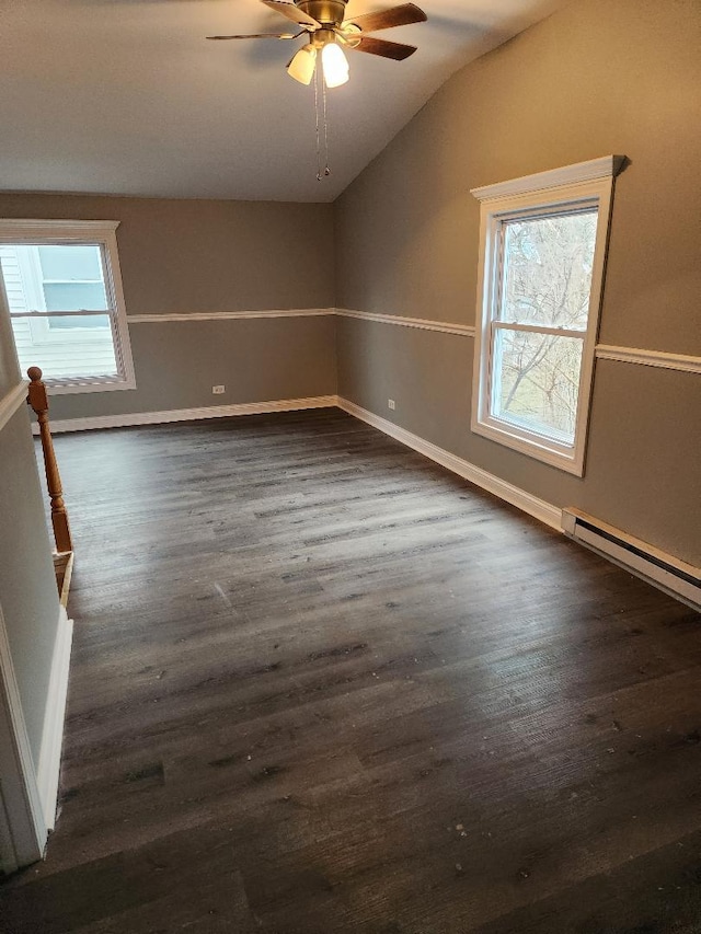 empty room featuring dark hardwood / wood-style flooring, vaulted ceiling, ceiling fan, and a healthy amount of sunlight