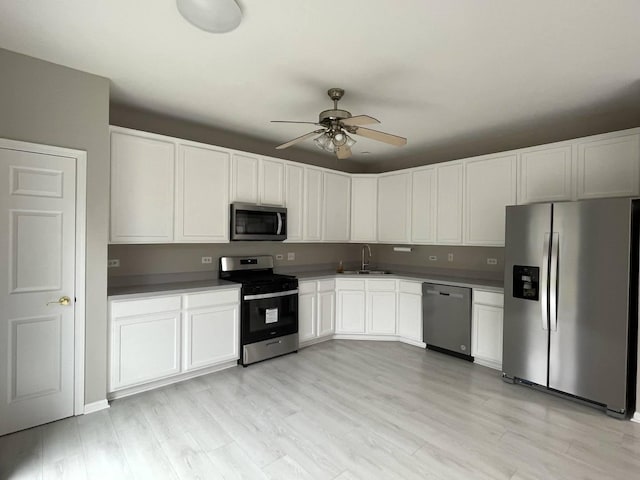 kitchen with sink, light hardwood / wood-style flooring, ceiling fan, appliances with stainless steel finishes, and white cabinetry