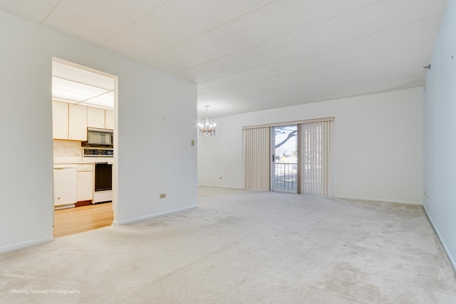 spare room with a notable chandelier and light carpet