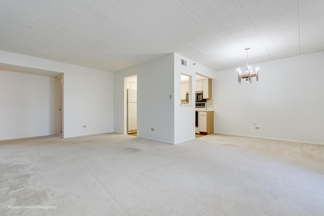 unfurnished living room featuring a notable chandelier and light colored carpet