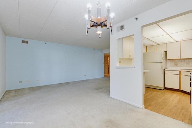 unfurnished living room with a chandelier and light colored carpet