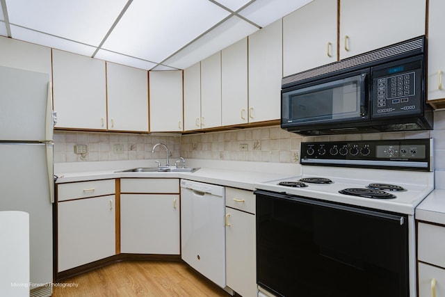 kitchen featuring backsplash, white appliances, sink, light hardwood / wood-style floors, and white cabinetry