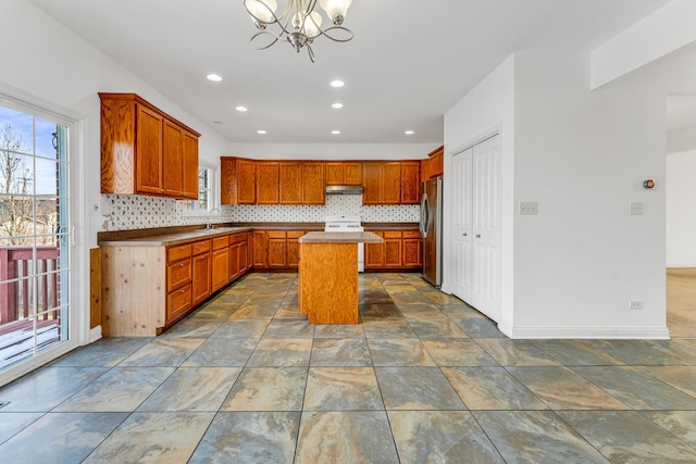 kitchen with stainless steel refrigerator, decorative light fixtures, decorative backsplash, a center island, and range