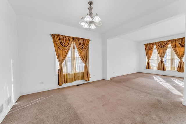 empty room featuring carpet flooring and a chandelier