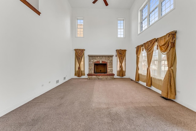 unfurnished living room featuring a high ceiling, ceiling fan, and carpet flooring