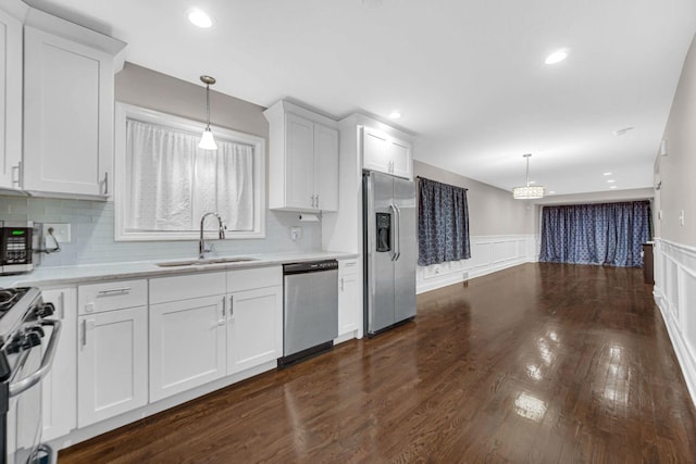 kitchen featuring sink, stainless steel appliances, backsplash, decorative light fixtures, and white cabinets