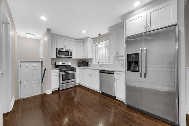 kitchen with sink, hanging light fixtures, tasteful backsplash, white cabinets, and appliances with stainless steel finishes