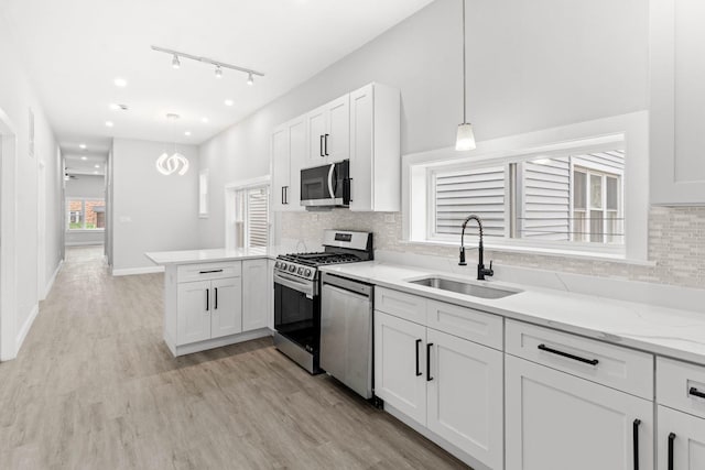 kitchen with sink, hanging light fixtures, white cabinetry, kitchen peninsula, and stainless steel appliances