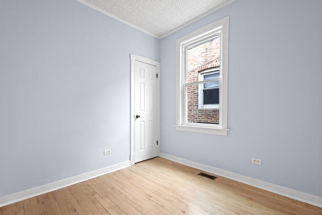 spare room with a textured ceiling and light wood-type flooring