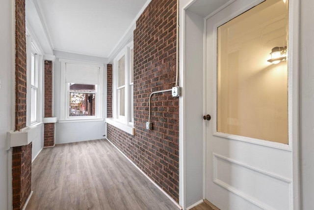 interior space with hardwood / wood-style flooring, crown molding, and brick wall