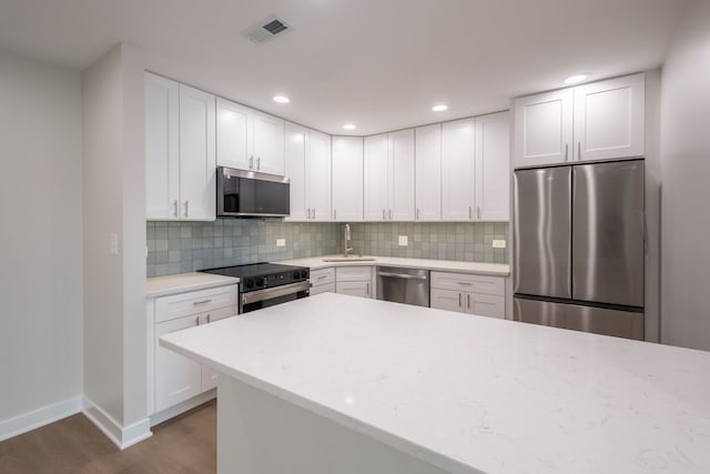 kitchen with appliances with stainless steel finishes, dark hardwood / wood-style floors, white cabinetry, and sink