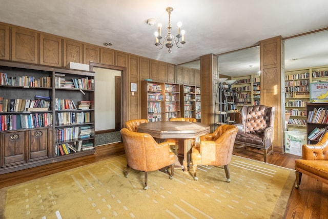 dining area with wood-type flooring, built in shelves, and a notable chandelier