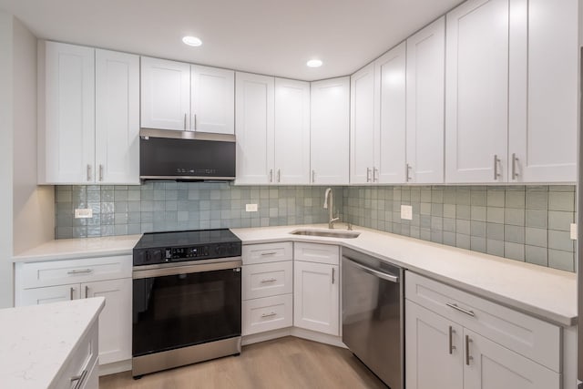 kitchen with stainless steel appliances, decorative backsplash, light wood-type flooring, white cabinets, and sink