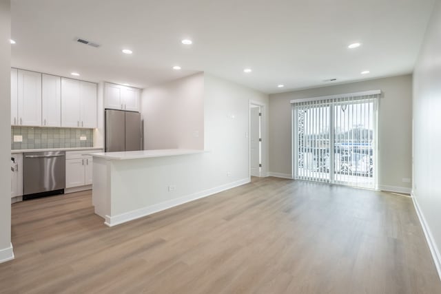 kitchen featuring appliances with stainless steel finishes, decorative backsplash, light hardwood / wood-style floors, and white cabinets