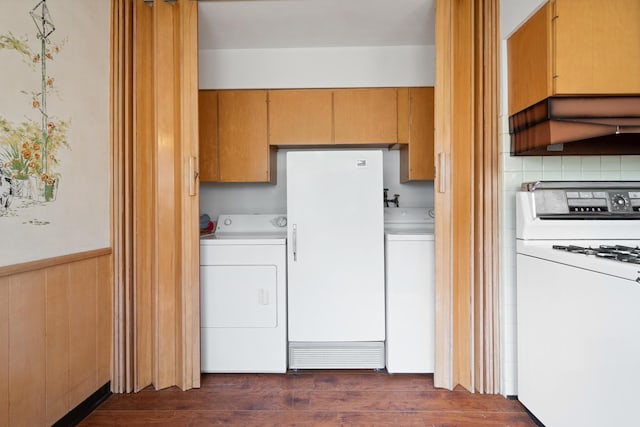 interior space featuring washing machine and clothes dryer, wood walls, dark hardwood / wood-style flooring, and cabinets