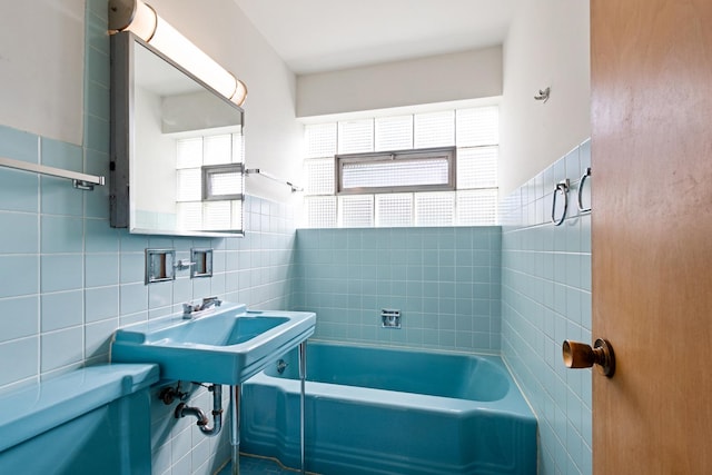 bathroom featuring a bath, tile walls, and sink