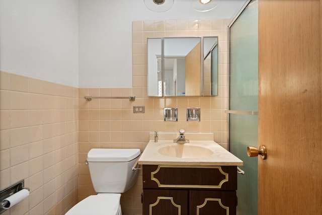 bathroom with vanity, toilet, and tile walls