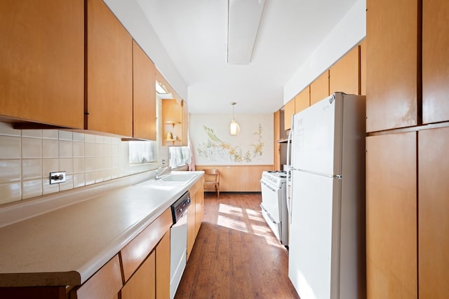 kitchen featuring backsplash, white appliances, dark wood-type flooring, sink, and pendant lighting