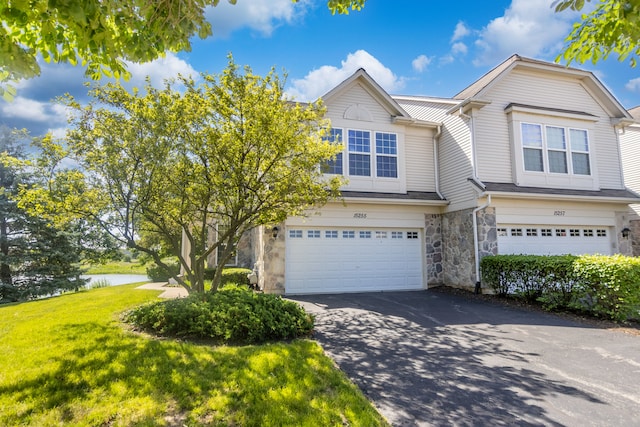 view of property with a water view, a garage, and a front lawn