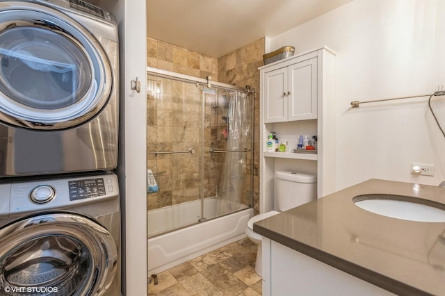 bathroom with stacked washer / drying machine, enclosed tub / shower combo, and vanity