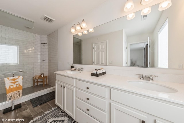 bathroom with a tile shower and vanity