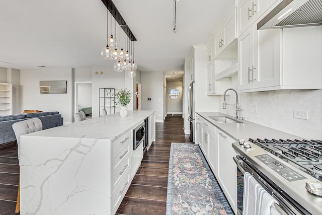 kitchen featuring white cabinetry, sink, stainless steel appliances, extractor fan, and a kitchen island