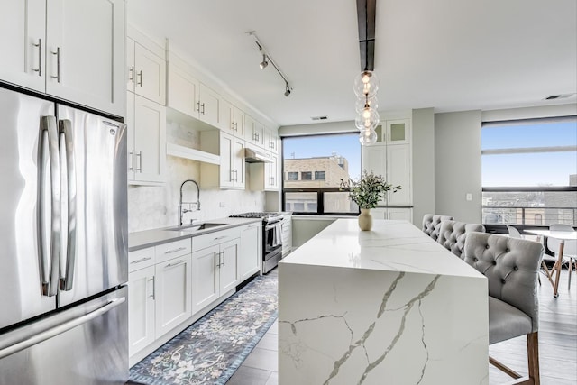 kitchen featuring appliances with stainless steel finishes, sink, a center island, white cabinetry, and hanging light fixtures