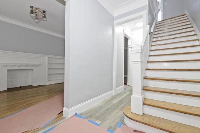 stairs with hardwood / wood-style flooring and crown molding