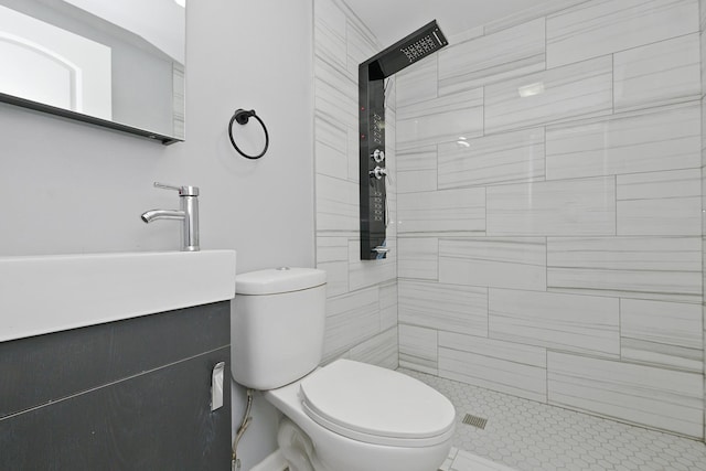 bathroom with vanity, toilet, and tiled shower