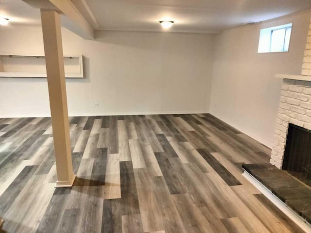 basement featuring a stone fireplace and dark hardwood / wood-style flooring