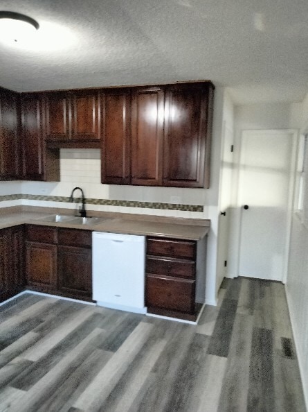 kitchen featuring dark brown cabinetry, sink, white dishwasher, wood-type flooring, and a textured ceiling