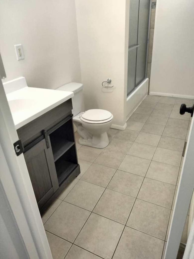 full bathroom featuring shower / bath combination with glass door, tile patterned flooring, vanity, and toilet